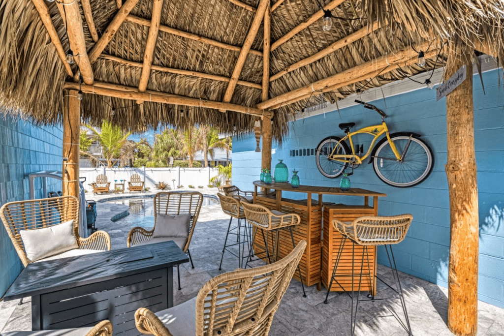 Tiki hut with pool, seating, and a yellow bicycle in Florida backyard.